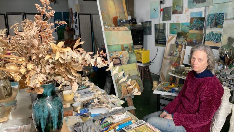 A woman poses with her paintings.