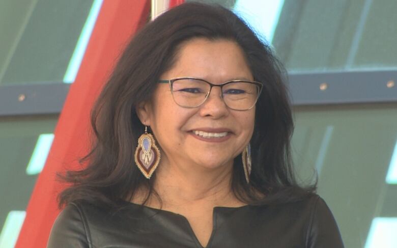 A dark-haired woman with glasses is smiling. 