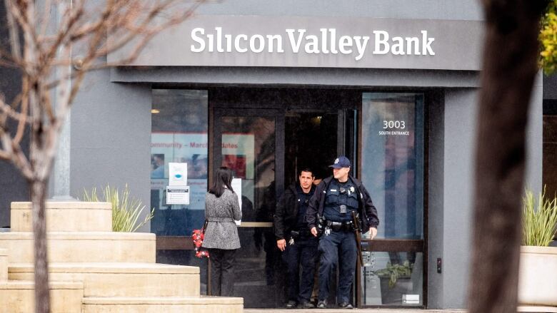 Two police officers exit a bank. 