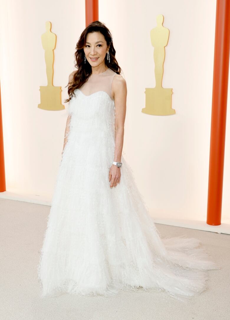 A woman wears a white feathery gown.