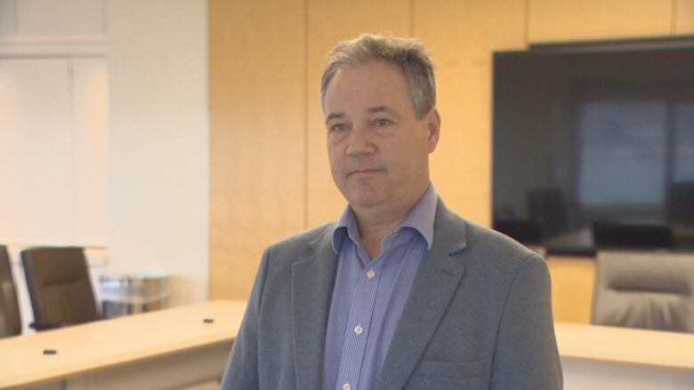 A man wearing a suit standing in a conference room. 