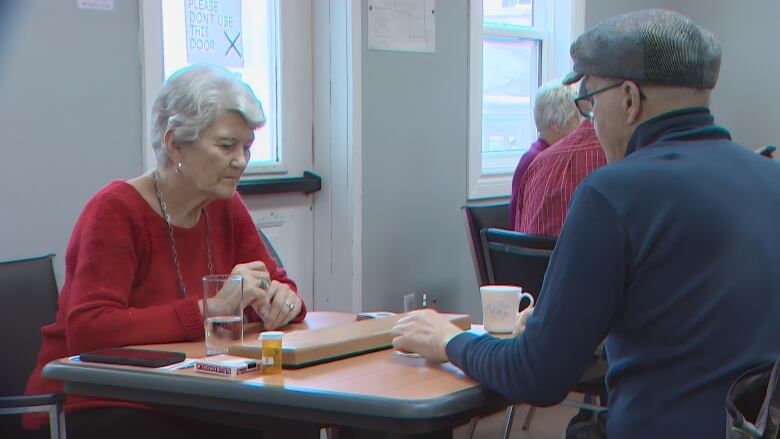 A man and a woman sit at a table playing cribbage