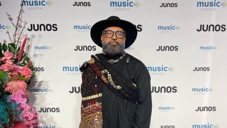 A man stands in traditional black South Asian attire on the Juno's red carpet. 