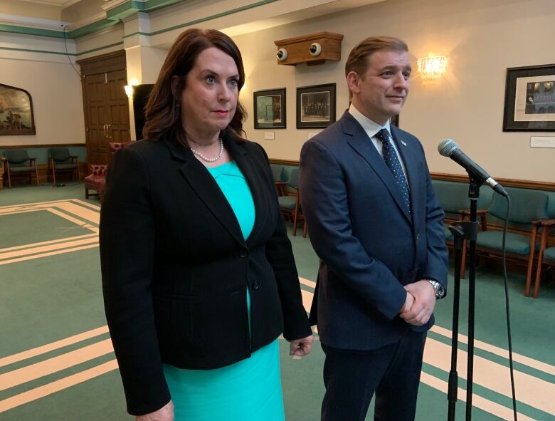 Two people stand at a microphone,