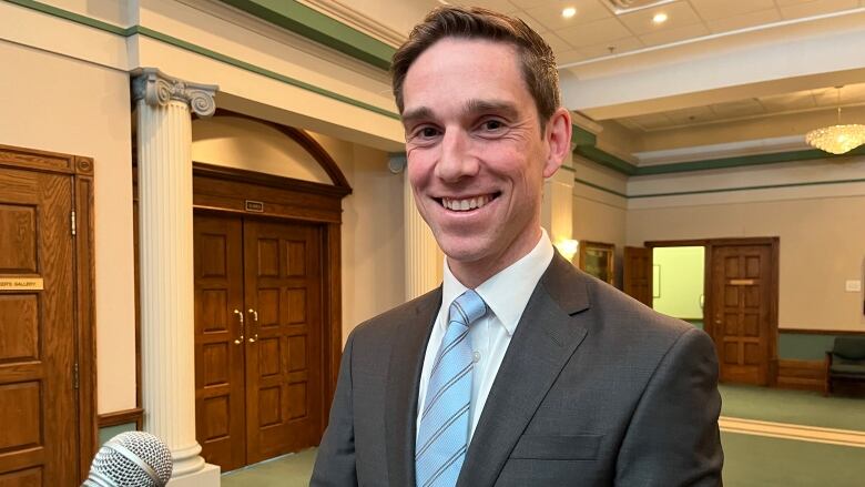 A man wearing a suit looks at the camera and smiles.