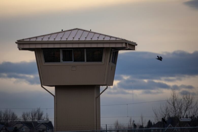 A prison tower is seen against a stormy sky.