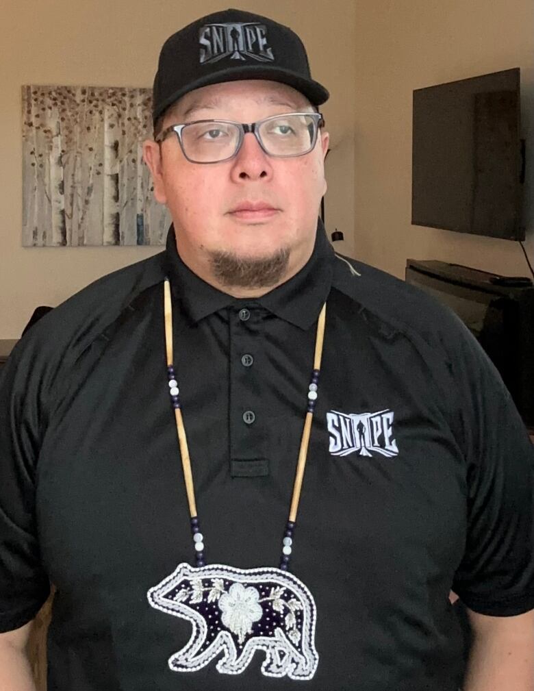 Photo of man wearing hat and beaded bear medallion.