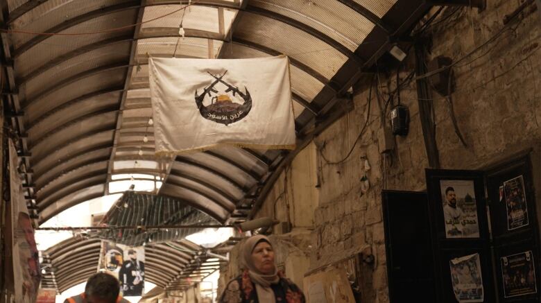 A flag hangs from the rafters in an old city.