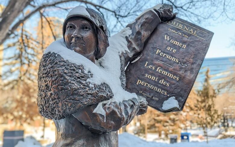 a bronze statue of a woman holding a paper that reads women are persons