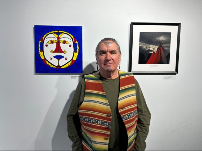 A man stands between a blue acrylic drawing and a photo of the moon.