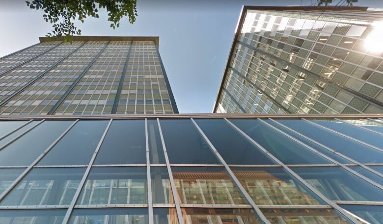 Two towers of a business complex rise from a slanted glass front at street level.