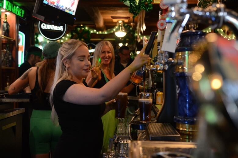 two servers smile and get beer from the tap