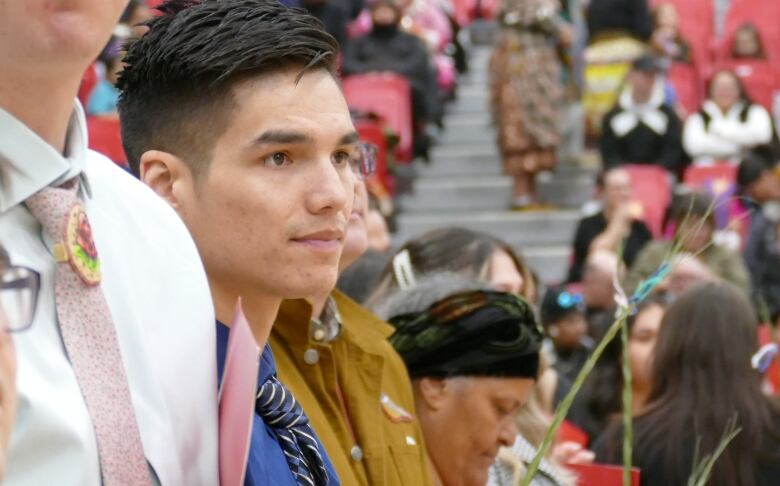 A man is standing with other people in a line, holding a red folder.