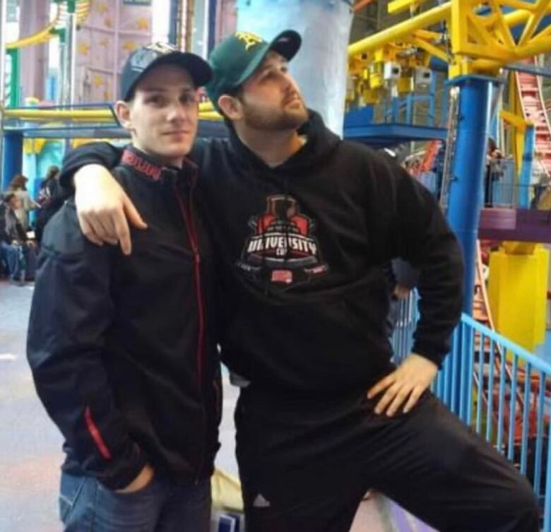 A man stands with his friend in a mall.