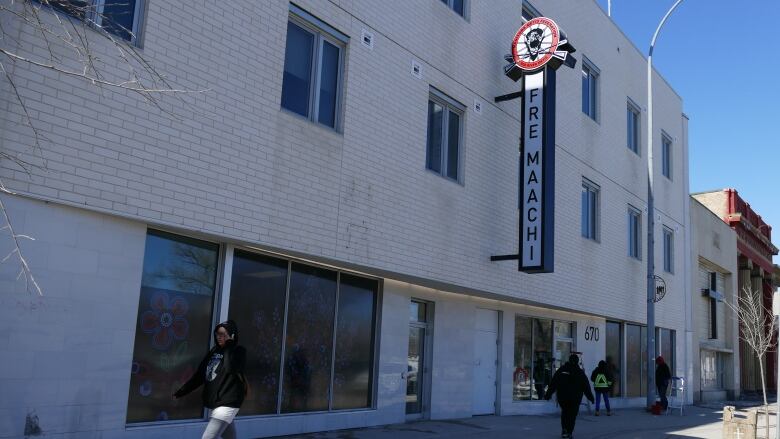 A three-storey building is shown with people walking by on the sidewalk.