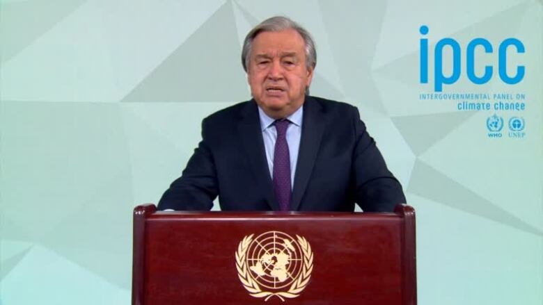 Antonio Guterres stands behind a podium with the UN logo.