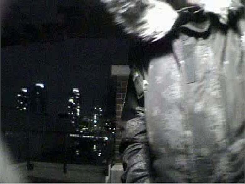 A blurry nighttime photo of a person with interest in a fur-rimmed hood is seen from the front, up close.