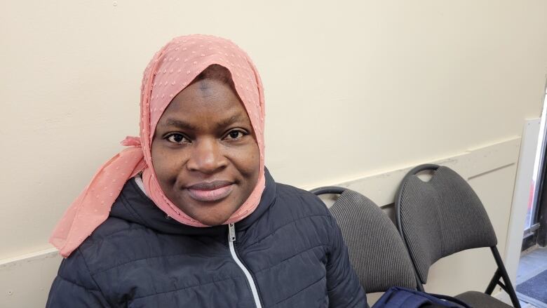 A woman wearing a pink head covering is pictured.