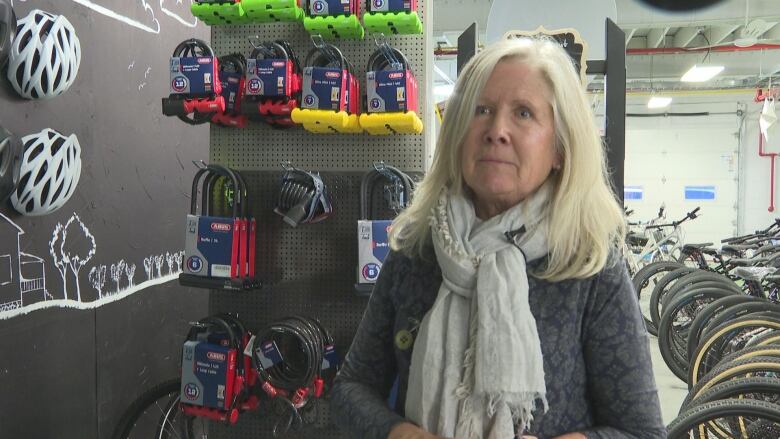 A woman stands in front of a wall of bike locks.