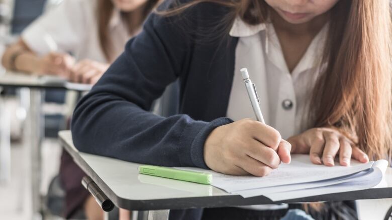 Student hand holding pen writing doing examination with blurred abstract background