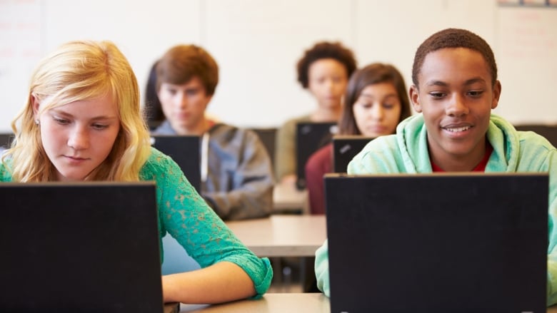 Group of high school students in class using laptop