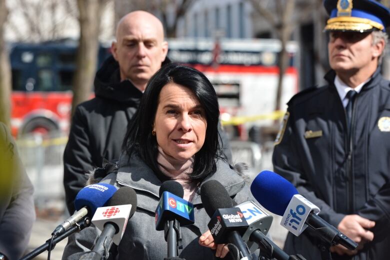 A woman is speaking with a police officer and a colleague behind her. 