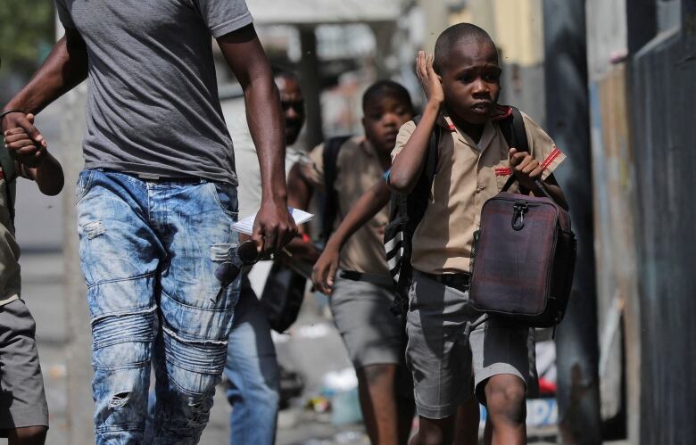 A child gestures as he looks for cover after leaving school amid gang violence in Port-au-Prince, Haiti March 3, 2023.