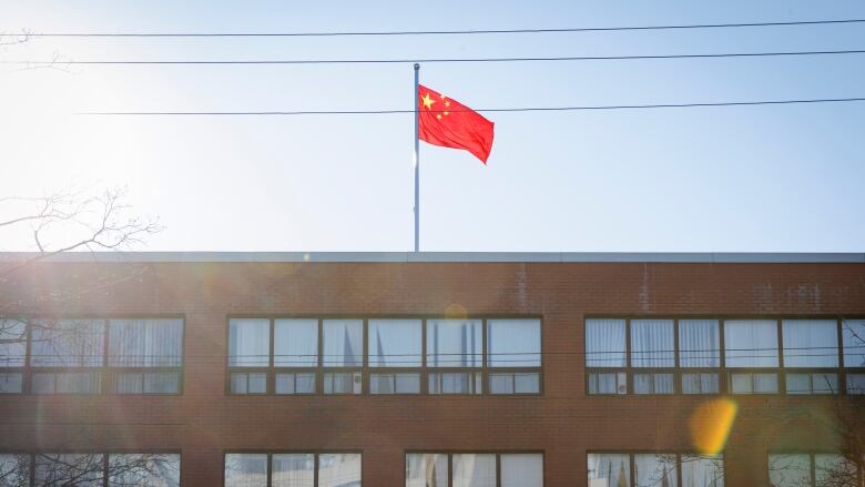 A red flag with five yellow stars is flying above the roof of a building.