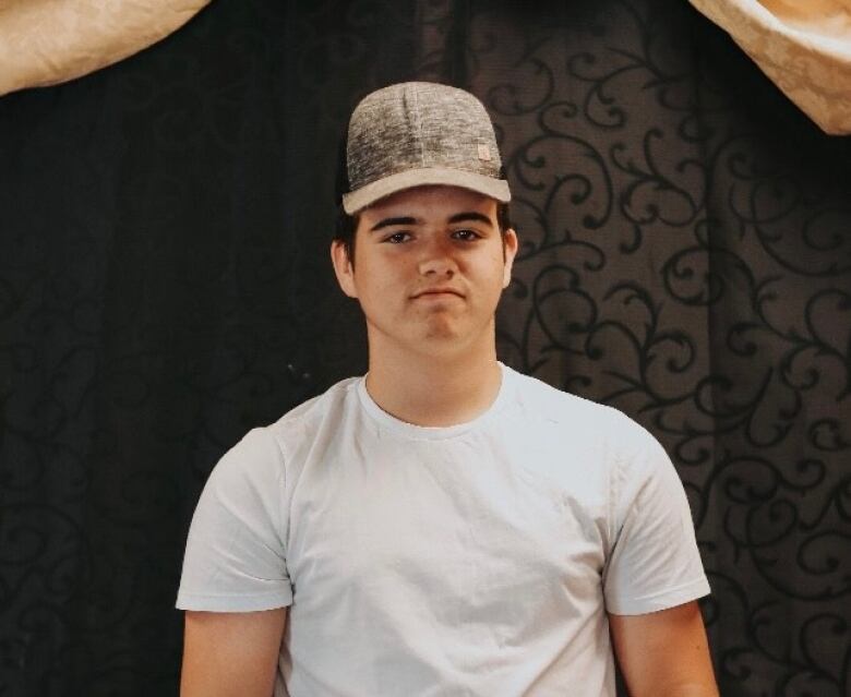 A teenager wearing a white shirt and a hat.