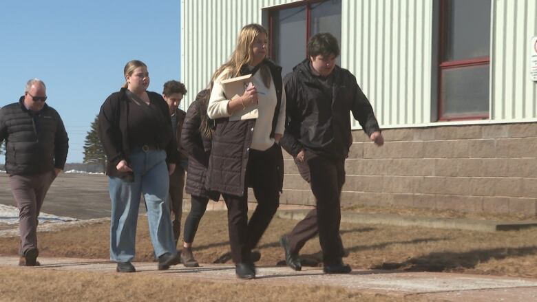 A group of people walking by a building.