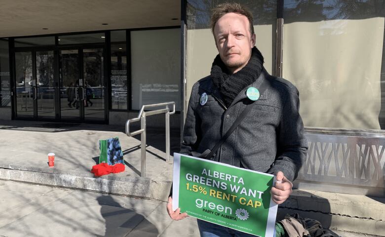 Guy stands holding sign saying 