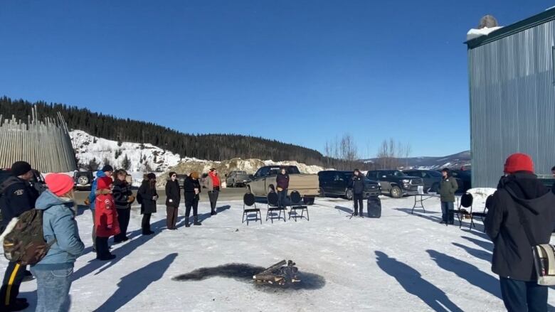 Group of people standing around a fire.