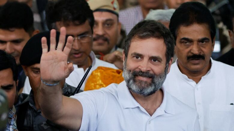 A bearded man is shown waving to unspecified persons not shown on camera.