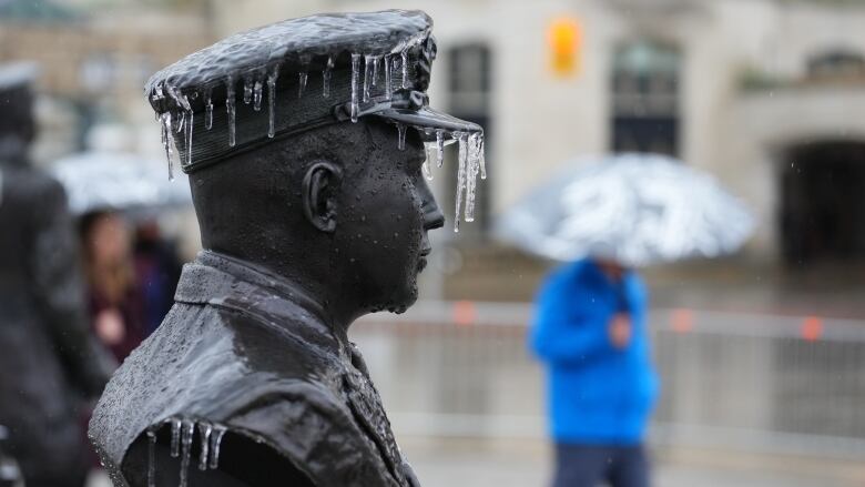 Small icicles hang off a statue of someone in a military uniform.