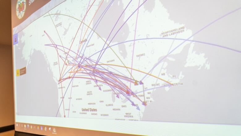 Coloured arrows dart all over a map of Canada shown on a projector screen.