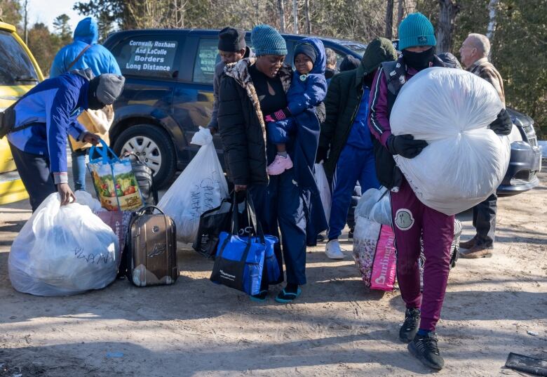 Asylum seekers cross the border at Roxham Road from New York into Canada on Friday, March 24, 2023 in Champlain, N.Y. The irregular border crossing will be closed permanently tonight at midnight. 