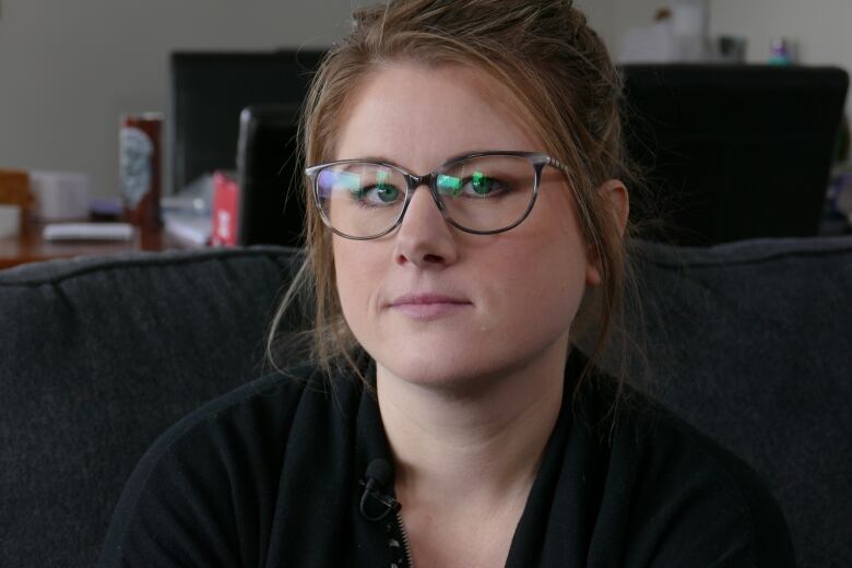 A woman wearing glasses is sitting on her couch. 