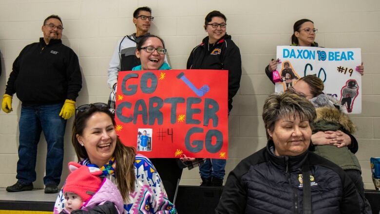 Fans hold signs cheering on their favourite hockey players.