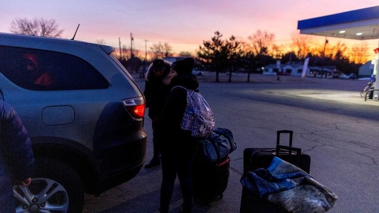 People stand near a taxi to cross into Canada at Roxham Road, an unofficial crossing point from New York State to Quebec, in Plattsburgh, New York, U.S. March 25, 2023.