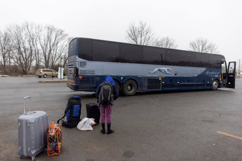 A young person waits with their families belongings after getting off a bus and waiting for a taxi to cross into Canada at Roxham Road, an unofficial crossing point from New York State to Quebec, in Plattsburgh, New York, U.S. March 25, 2023. 