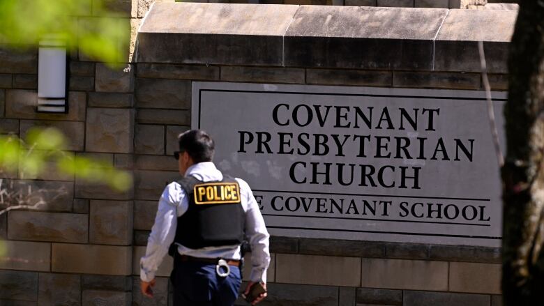 A police officer walks past a sign for a school.