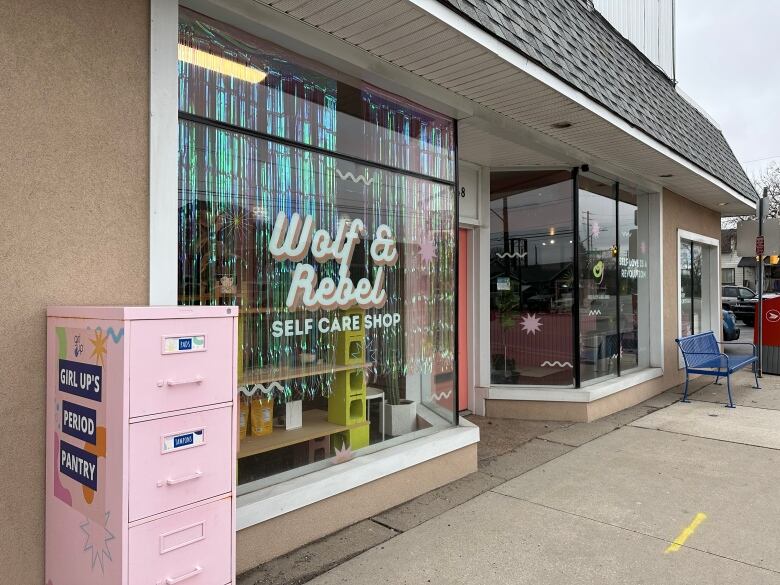 A storefront with a pink filing cabinet outside