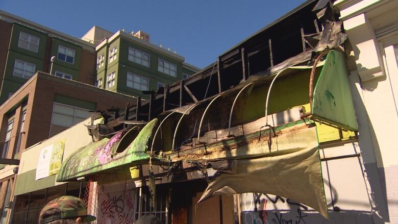 A photograph of a burned building in Vancouver. Burned awning and a charred structure are displayed.