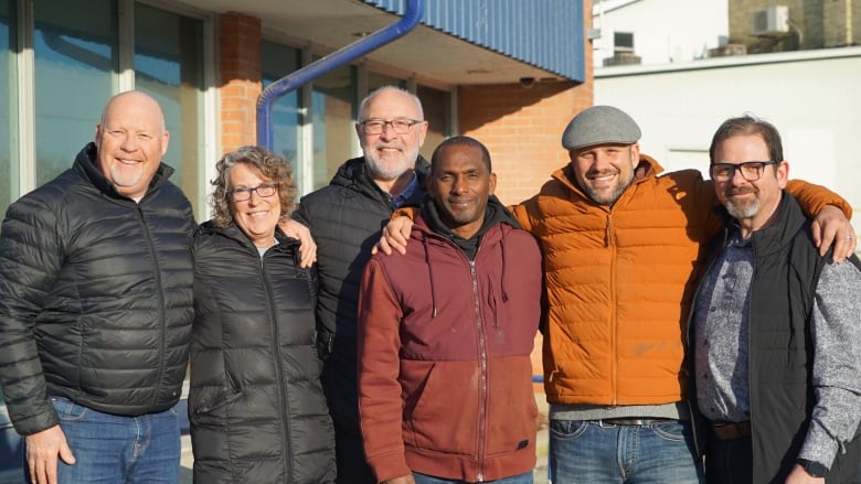 A group of people with their arms around one another.