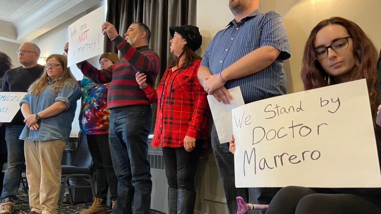 A group of people gather holding signs.