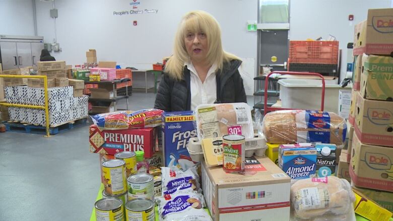 June Muir, president of the Windsor-Essex Food Bank Association, stands in front of about $200 worth of groceries, about the same amount the rebate could buy.