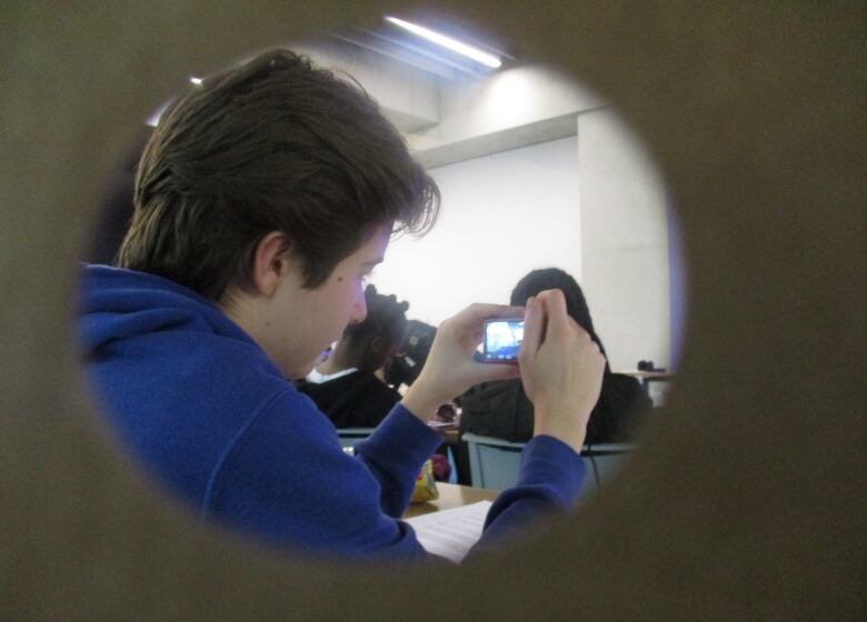 A boy is framed by circles. He's also looking in a camera. 