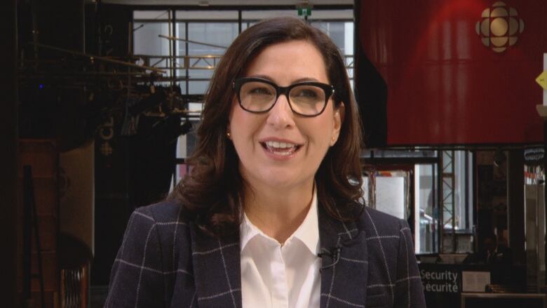 Woman with brown hair and glasses smiling.