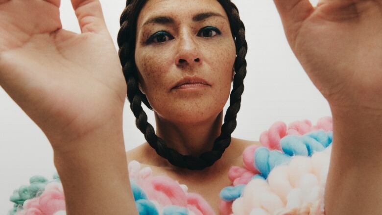 Inuk woman raises hands in foreground.