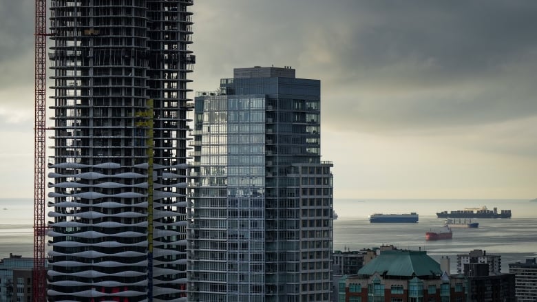 A condo tower is seen under construction in downtown Vancouver as freighters sit at anchor on English Bay.